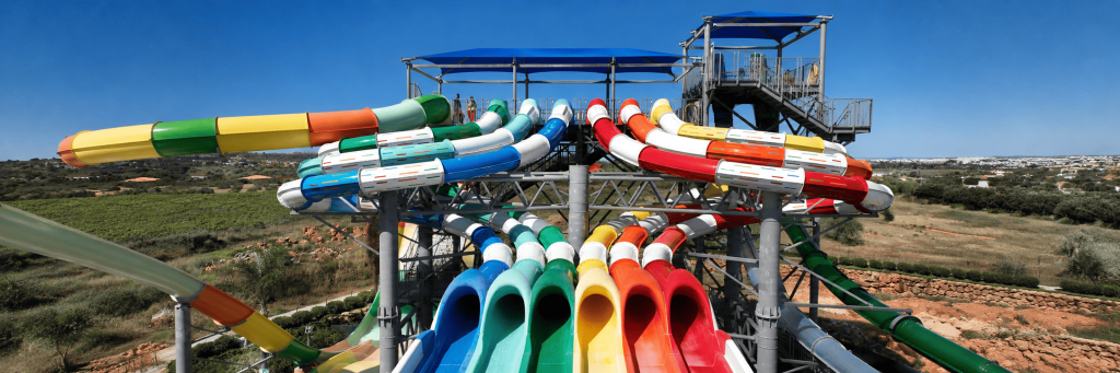 imagem de drone de seis escorregas do slide & splash com diversas cores nesta ordem: azul escuro, azul clarinho, verde, amarelo, laranja e vermelho.