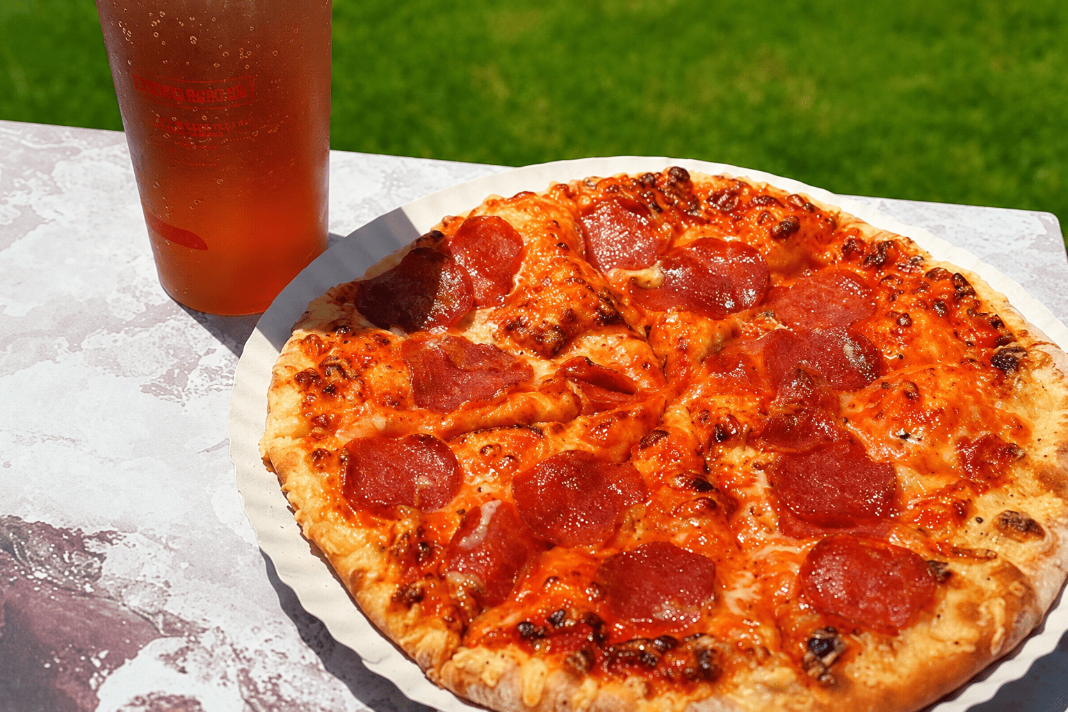fotografia aproximada de uma pizza de pepperoni e um sumo num copo do slide & splash