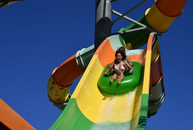 Visitante a descer um escorrega com boia verde no Slide & Splash
